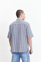 Camisa de manga corta con corte oversize, a rayas verticales blancas y grises, con cuello clásico y cierre frontal con botones. Confeccionada en algodón.