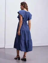 Vestido midi celeste de poliéster, con cuello a la base y escote en V. Presenta cintura con frunces y lazo de ajuste, mangas ranglan con sisa amplia y falda escalonada. Marca Emma & Michele.