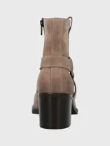 Bota corta de cuero color taupe, con caña de 14 cm, taco cuadrado de 6 cm y punta cuadrada. Presenta una correa con hebilla metálica alrededor del tobillo y cierre lateral.
