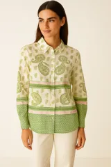 Camisa de viscosa color crema con estampado de cachemir en verde y detalles en rosa. Tiene cuello camisero, cierre frontal con botones y corte holgado.