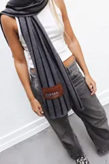 Bufanda tejida en técnica de jacquard con patrón de rayas verticales y parche en paño con bordado.