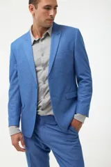 Ambo de traje azul marino, compuesto por saco de solapa en punta y pantalón a juego. Se combina con una camisa azul oscuro desabrochada.