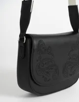 Bandolera negra de cuerina con solapa bordada y correa regulable de tela con rayas blancas y negras.