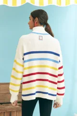 Sweater de punto grueso color crudo, con cuello alto con cierre de cremallera y rayas horizontales en azul, amarillo y rojo.