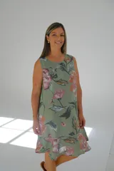 Vestido corto verde con estampado floral en tonos rosa y naranja, sin mangas y con ruedo con volantes.
