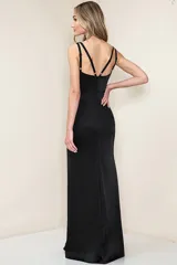 Vestido largo negro de satén con escote en V, sin mangas, corte a la cintura y falda con abertura lateral.