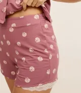Conjunto de pijama americano corto, color rosado con estampado de caracolas. Incluye camisa de manga corta con cuello solapa y abotonado delantero, y short con cintura elástica y detalle de encaje en el ruedo.