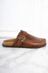 Zueco de cuero color marrón con diseño trenzado en la puntera, hebilla metálica ajustable y plantilla de corcho.