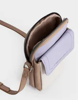 Porta celular de cuerina texturada con bolsillo frontal con solapa, correa regulable, acceso mediante cierre superior y puller de cuerina estampada, solapa con broche con botón para cerrado y tag de metal.