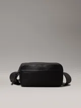 Bolso bandolera negro de Calvin Klein, confeccionado en piel sintética suave. Tiene correa ancha ajustable, cierre de cremallera, bolsillo exterior y bolsillo interior.