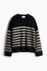 Buzo de punto suave con lana y mohair en la trama, diseño a rayas horizontales en blanco y negro, corte amplio con hombros caídos y terminaciones acanaladas.