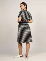 Vestido a la rodilla de algodón a rayas horizontales en color negro y beige, con cuello redondo, mangas cortas y cinturón azul marino.