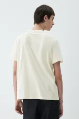 Remera de punto liviano color crema, con cuello redondo ribeteado y bajo recto. Corte estándar. Confeccionada con tejido funcional COOLMAX®, una fibra exclusiva de poliéster de secado rápido que elimina la humedad y regula la temperatura corporal.