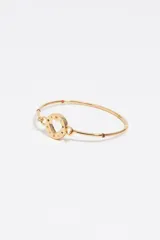 Pulsera rígida dorada con un dije central circular que tiene un corazón calado. El borde del dije tiene letras esmaltadas en colores. El cuerpo de la pulsera tiene pequeñas cuentas de colores incrustadas.