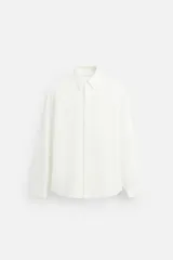 Camisa color crudo de corte relaxed fit, confeccionada en tejido de algodón con estructura jacquard. Tiene cuello solapa, manga larga con puños abotonados y cierre frontal con botones.