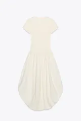 Vestido largo color crema, con cuello redondo y mangas cortas. Presenta corte a la altura de la cintura y falda amplia con terminación redondeada tipo globo.