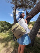 Mochila urbana de diseño compacto, color violeta/malva, con acabado ligeramente brillante. Presenta un compartimento principal con doble cierre superior y bolsillos laterales con cierre.