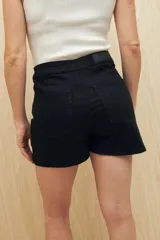 Minifalda de jean azul oscuro con botones metálicos plateados en el frente.