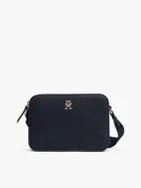 Bandolera Tommy Hilfiger color azul marino, de forma rectangular con logo dorado en el frente y correa de tela con inscripción de la marca.