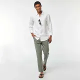 Camisa blanca de lino de corte regular, con cuello clásico, manga larga con puños abotonados y cierre frontal con botones.