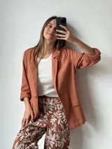 Blazer color ladrillo de lino con corte clásico, solapas y bolsillos frontales.