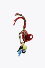 Llavero metálico con mosquetón dorado y charms colgantes desmontables: corazón rojo con espejo interior, llave, pelota de tenis, tiburón azul y bola de billar número 8.