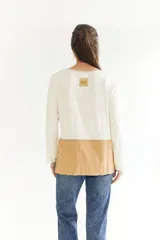 Remera de algodón color blanco con manga larga, corte irregular y franja lateral color beige.