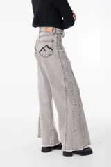 Pantalón de jean color gris claro con corte amplio y detalles de costura.