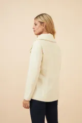 Chaquetón color crema con doble solapa, abrochadura doble, bolsillos delanteros y forro al tono.