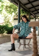 Camisa verde con estampado de flores blancas, cuello clásico, cierre frontal con botones y mangas globo.