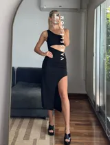 Vestido midi negro con corte asimétrico, una manga, abertura lateral y frunce en la cintura.