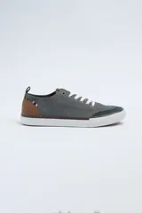 Zapatillas acordonadas de lona color gris con detalles en marrón y azul marino. Suela de goma blanca.