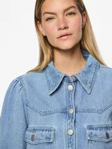 Camisa de jean celeste de algodón, corte regular, cuello clásico, mangas largas, bolsillos en el pecho y cierre con botones.