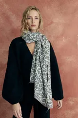 Bufanda rectangular color gris con estampado animal print y flecos cortos en los extremos.
