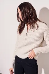 Sweater de tejido acanalado color beige melange, con medio cierre y corte al cuerpo.