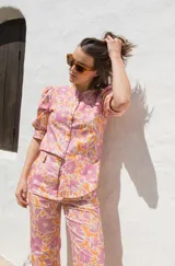 Camisa de lino estampada con flores en tonos rosa y naranja, con cuello mao, mangas cortas abullonadas y cierre frontal con botones.