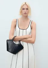 Vestido midi color crudo con tirantes anchos y escote cuadrado. Presenta ribetes negros en cuello, sisas y costuras verticales.