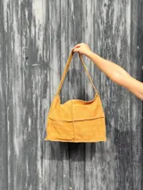 Bolso de hombro color ocre, con textura tipo piel de cocodrilo y asa corta.