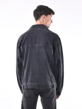 Campera de jean negra con cuello clásico, cierre frontal con botones metálicos, bolsillos con solapa en el pecho y corte recto.