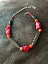 Collar corto con cuentas de resina rojas y naranjas, piedras rojas irregulares y cuentas de madera marrón.