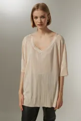 Blusa color beige con textura plisada, escote en V y mangas cortas amplias.