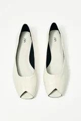 Zapato plano tipo bailarina de piel color crema con efecto craquelado y punta cuadrada abierta.
