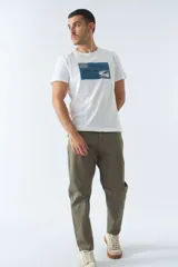 Remera blanca de algodón con cuello redondo y mangas cortas. Estampado frontal con diseño rectangular en tonos azules que incluye texto, coordenadas y la imagen de un avión.