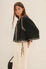 Camisa blanca de algodón con bordado negro en el ruedo, corte amplio y largo corto. Escote redondo y mangas largas abullonadas.