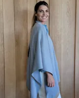 Ruana negra de tejido de punto con una estrella grande color beige en la espalda y borde inferior con franja beige.