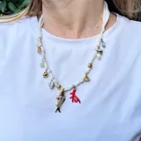 Collar corto hecho en pañuelo marrón con mix de dijes dorados, rojos y blancos.