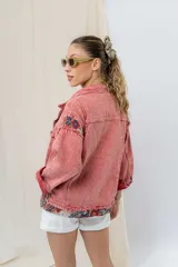 Campera de jean oversize, color rojo desgastado, con aplicaciones de tapicería multicolor de estilo étnico en hombros y ruedo, y terminaciones desflecadas.