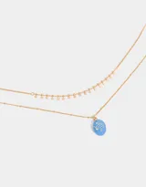 Collar corto dorado multicadena con dije ovalado celeste con estrellas y dijes de estrellas colgantes.