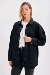 Sobrecamisa de jean negro con cuello clásico, cierre frontal con botones a presión, dos bolsillos con solapa en el pecho y corte holgado.