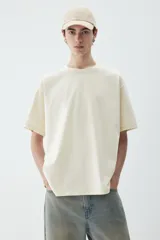 Remera color crema de punto pesado con cuello redondo ribeteado, hombros caídos y bajo recto. Corte holgado confeccionada con tejido funcional Coolmax, una fibra de poliéster de secado rápido que elimina la humedad y regula la temperatura corporal.